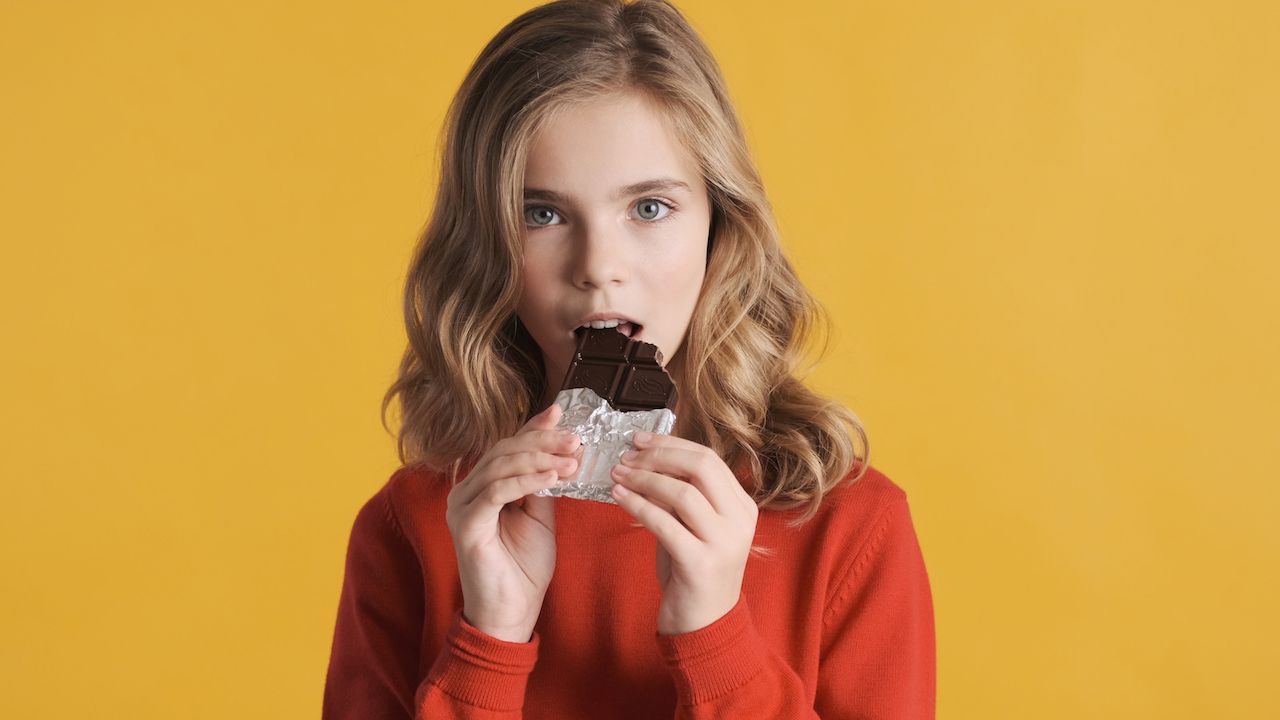 beautiful-blond-teenager-girl-eating-chocolate-bar-isolated-yellow-background-sweet-tooth-girl.jpg