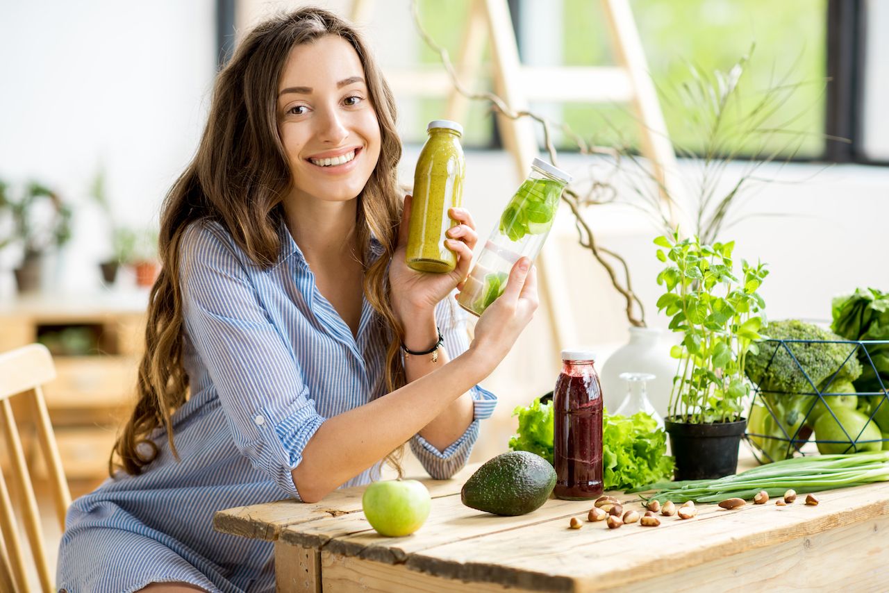 beautiful-happy-woman-sitting-with-healthy-green-food-drinks-home-vegan-meal-detox-concept.jpg