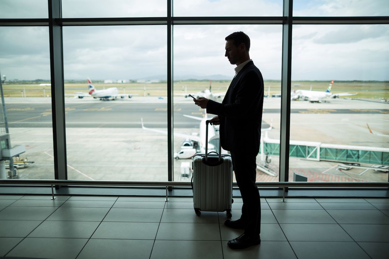 businessman-with-luggage-using-mobile-phone.jpg