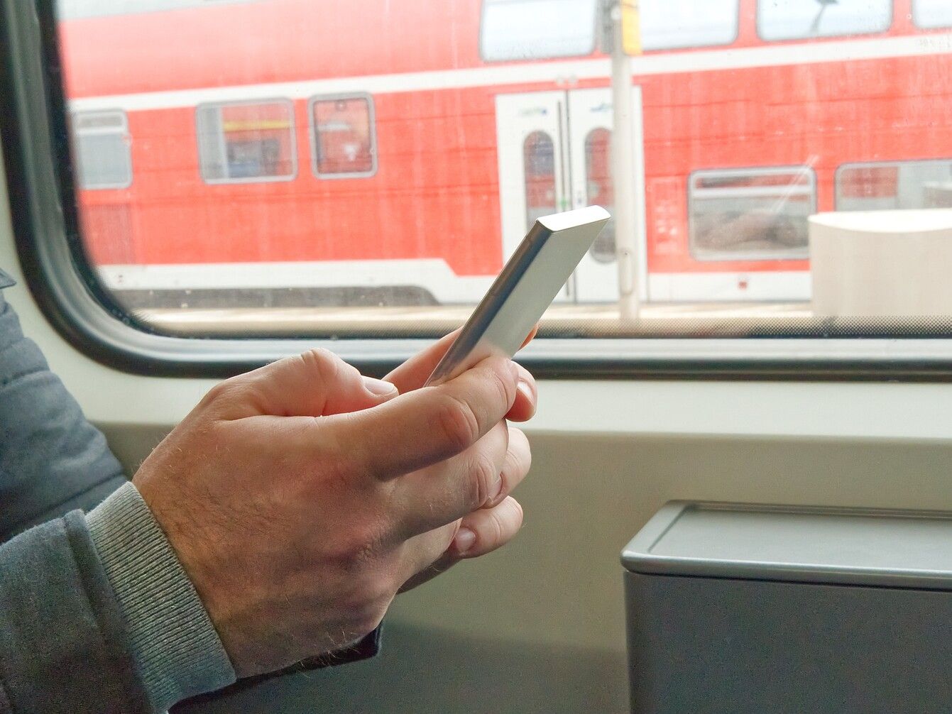 cropped-hand-man-using-mobile-phone-train (1).jpg