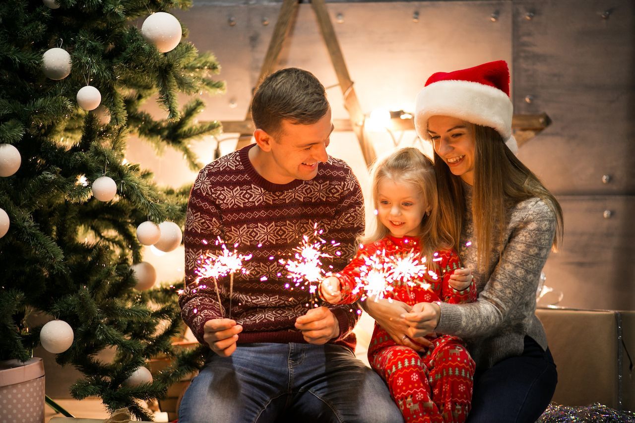 family_sitting_by_christmas_tree_with_bengal_lights_dd95cccd1b.jpg