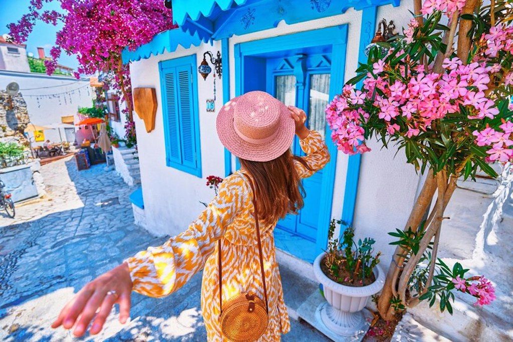 follow-me-concept-girl-traveler-wearing-dress-hat-walks-beautiful-colorful-flower-street-with-white-houses-blue-doors-european-city_122732-5033.jpg