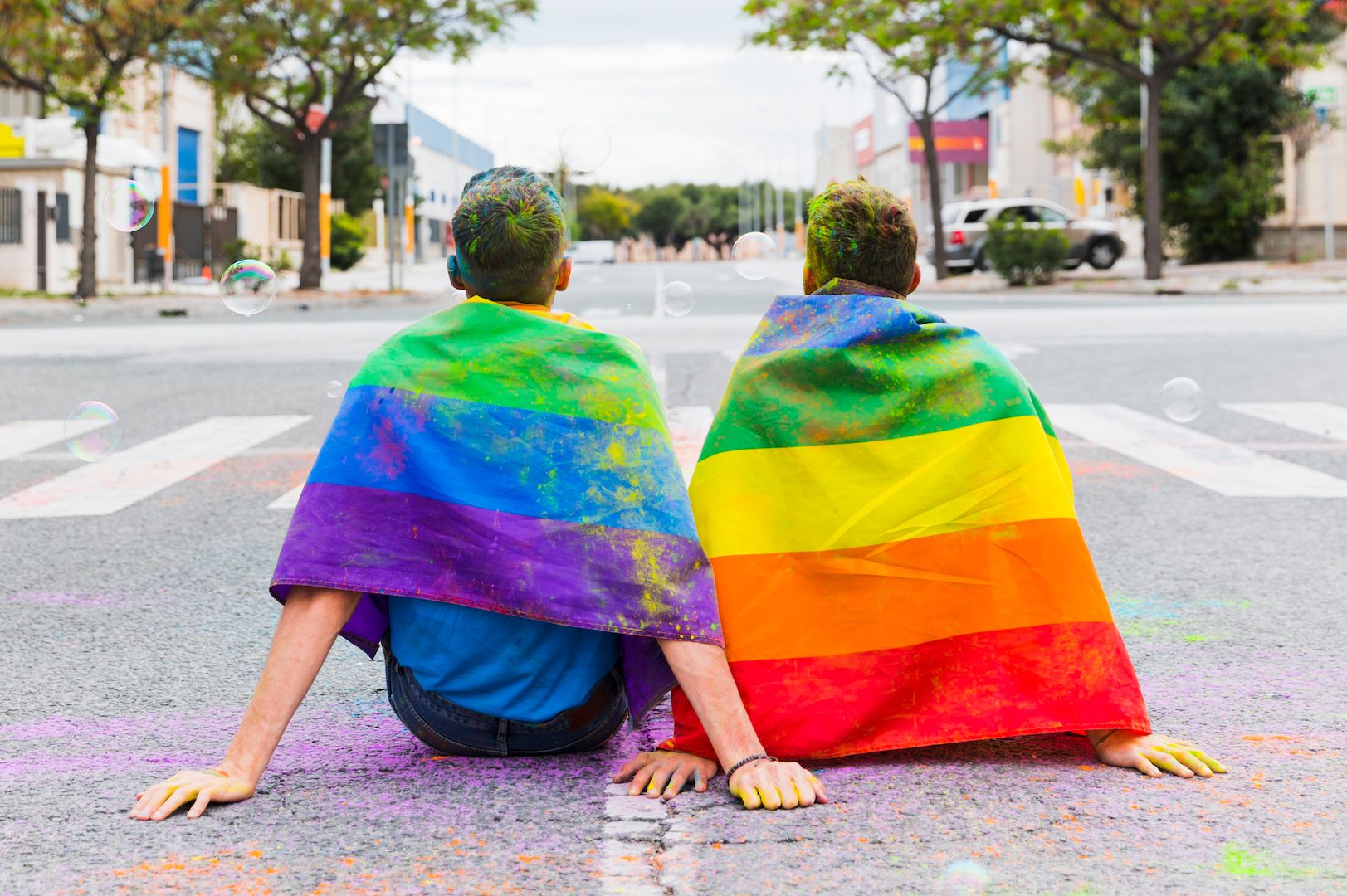 gay-with-rainbow-flags-sitting-street.jpg