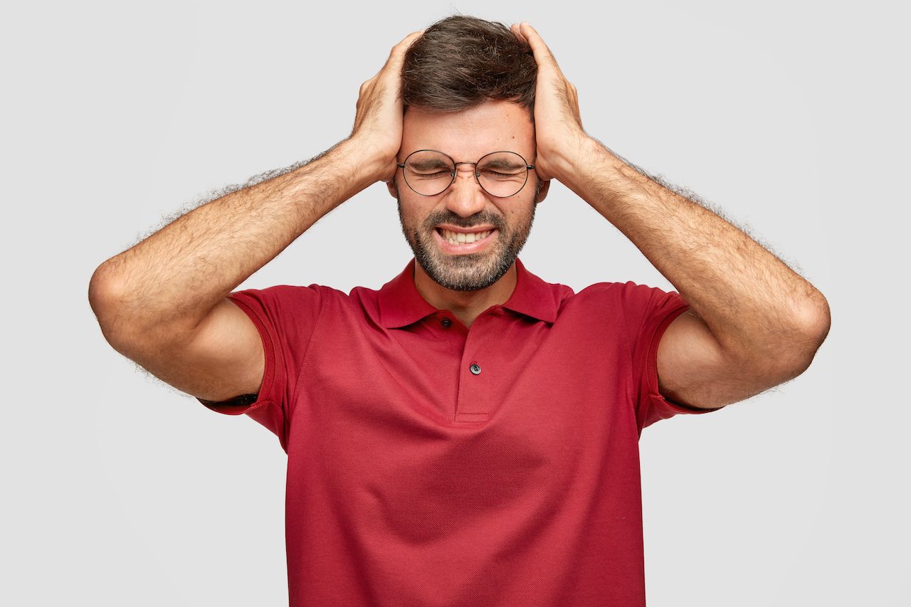 horizontal-shot-fatigue-young-euroepean-unshaven-male-keeps-hands-head-feels-exhausted-after-work-office-has-headache-wears-casual-bright-red-t-shirt-isolated-white-wall.jpg