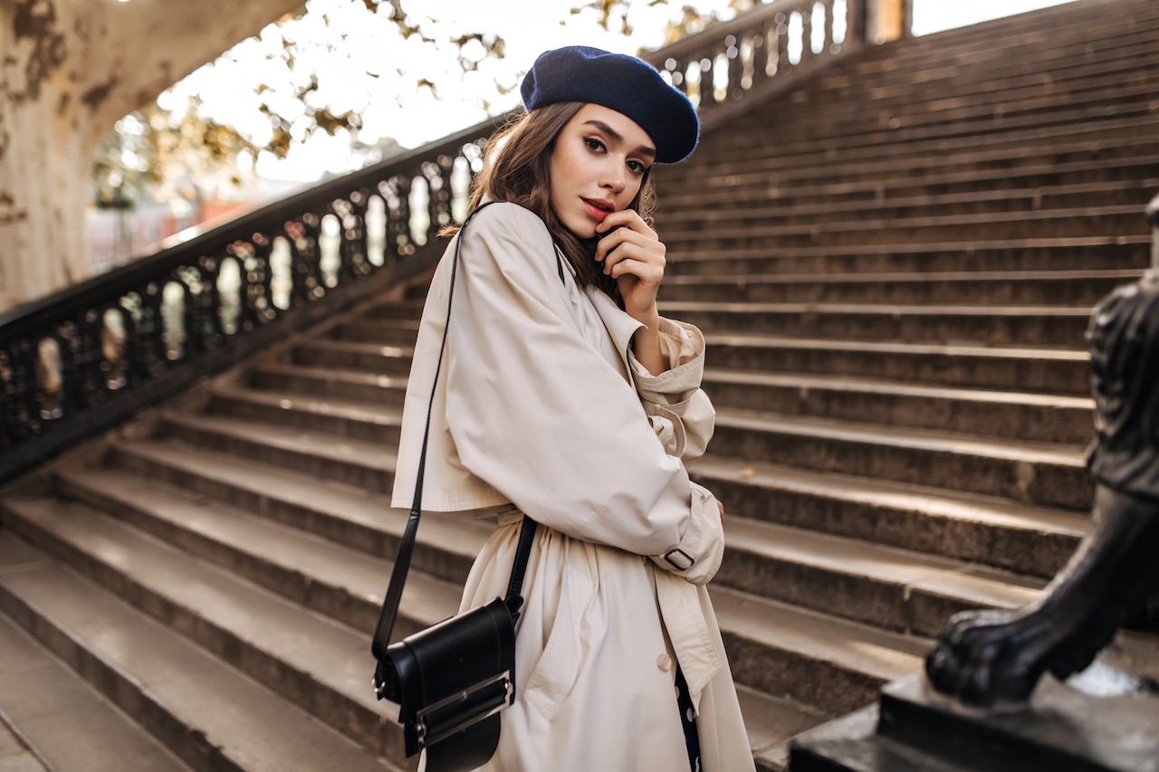 lovely-young-parisian-woman-with-brunette-hair-stylish-beret-beige-trench-coat-black-bag-standing-old-stairs-sensitively-posing-outdoors.jpg