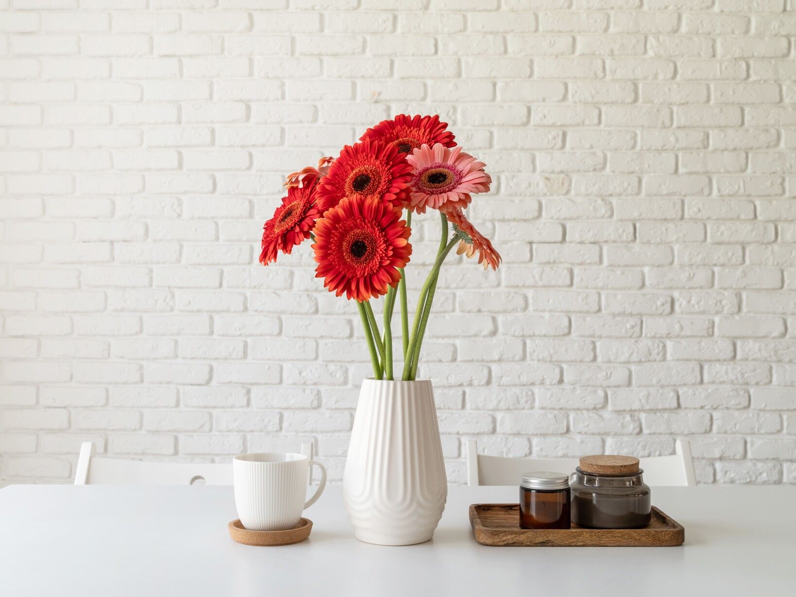 red-pink-gerbera-daisies-white-vase-kitchen-table-with-candles-cup-minimal-style (1).jpg