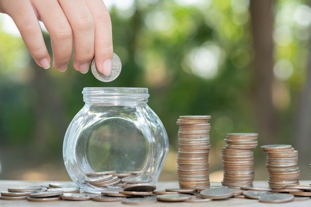 saving-money-concept-preset-by-male-hand-putting-money-coin-stack-growing-business-arrange-coins-into-heaps-with-hands-content-about-money_1150-45705.jpg