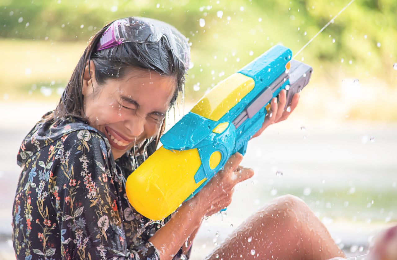 side-view-woman-spraying-water-from-gun-while-sitting-outdoors.jpg
