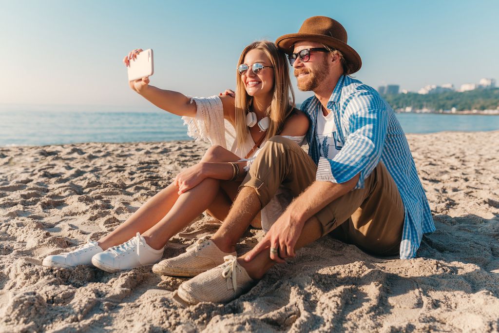 young-attractive-smiling-happy-man-woman-sunglasses-sitting-sand-beach-taking-selfie-photo.jpg